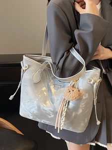 Silver metallic tote bag with marbled texture and cute teddy bear charm on model