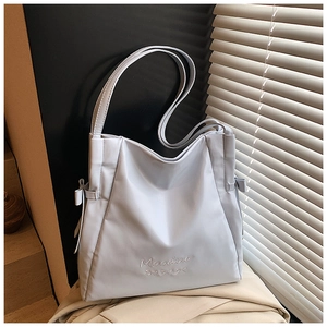 Detail of white tote bag with elegant bow embroidery and Mooduo branding on soft leather