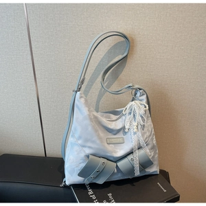 Detail view of a light blue tie-dye tote bag with rivets and pearl lace charm