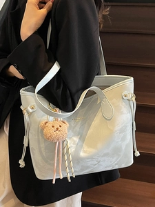 Light blue tote bag with marble texture and bear charm worn by model in black blazer