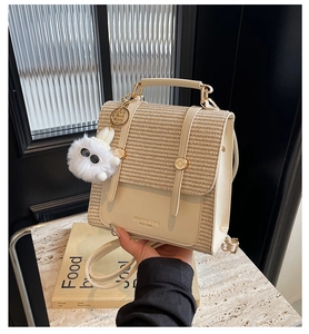 Detail shot of a woven and leather crossbody bag with a white plush monster charm