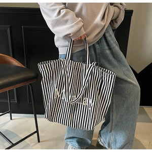 Detail of large black and white striped canvas tote bag featuring Monday printed text