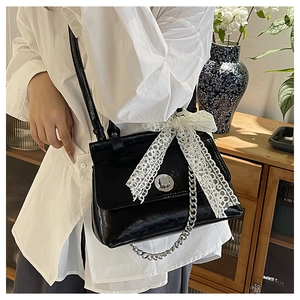 Détail du sac bandoulière en cuir ciré avec nœud en dentelle et chaîne argentée