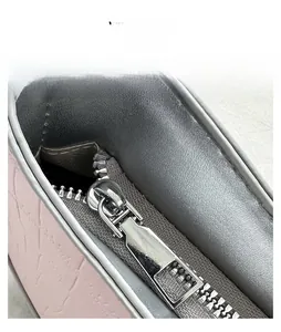 Detailed macro view of the smooth silver metal zipper and pink faux leather bag material
