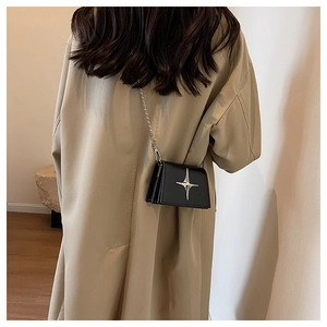 Mini black leather crossbody bag with silver star detail and chain strap worn by model