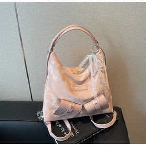Detail of pink satin tote bag featuring oversized bow, lace pearl charms and silver rivets