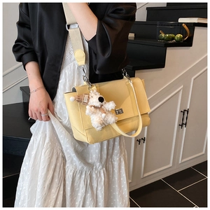Detailed texture of yellow lychee leather bag with metal lock and cute bear charm