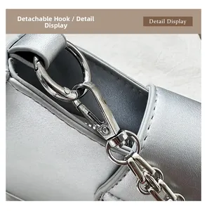 Detail view of the silver handbag featuring a shiny detachable metal hook and strap ring