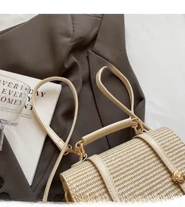 Detail of woven cream handbag featuring smooth long shoulder strap and golden metal buckle