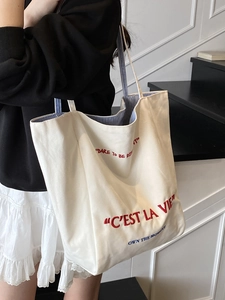 Large white canvas tote bag with embroidery and blue striped straps for daily commute