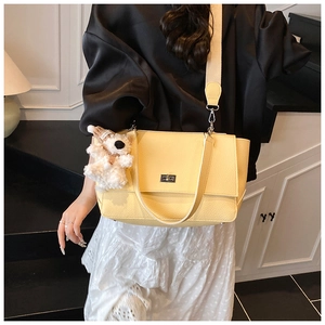 Close-up of yellow leather briefcase with silver metal buckle and plush bear charm