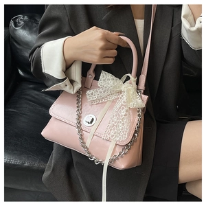 Détail du sac à main en cuir verni rose avec nœud en dentelle et chaîne argent