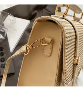 Close-up of woven straw texture and gold metal ring hardware on cream square handbag