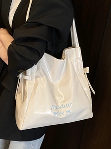 Minimalist white faux leather tote bag with blue bow embroidery and side ribbon details