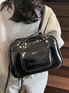Polished black faux leather crossbody bag with Noronoro logo on a model background