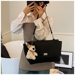 Detail view of black tote bag with silver twist lock and cute white plush bear pendant