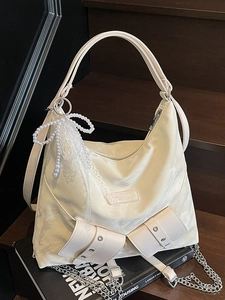 Chic cream tote bag with pearl lace charm and versatile straps on wooden stairs