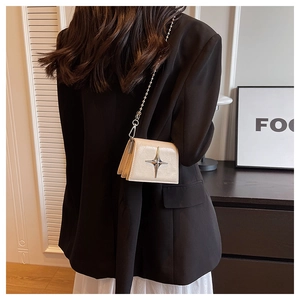 Detail of a creamy beige mini crossbody bag with a silver star and elegant bead chain