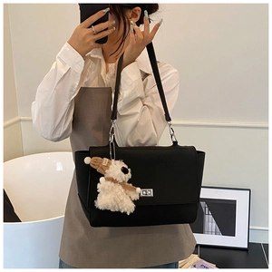 Detail of black leather briefcase bag with silver twist lock and plush puppy charm