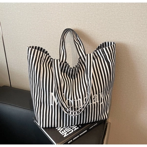 Detail of striped canvas tote bag with Monday embroidery and dual handle design
