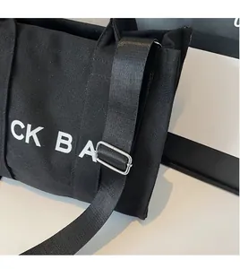 Detail shot of the black canvas tote bag showing the adjustable nylon shoulder strap