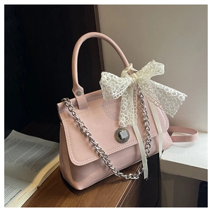 Détail du sac en cuir verni rose avec nœud en dentelle et chaîne en métal argenté