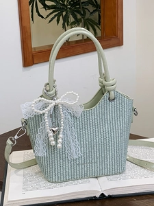 Sac seau tissé vert avec nœud en dentelle et perles posé sur un livre ancien