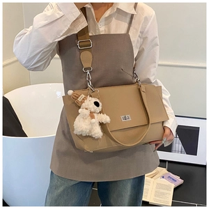 Close-up of khaki pebbled leather handbag with silver twist lock and plush charm accessory