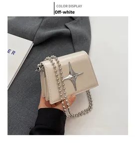 Detail of off-white mini bag featuring cracked leather texture and silver star buckle