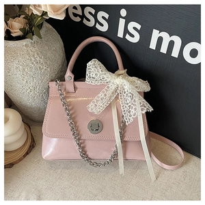 Gros plan du sac à main en cuir verni rose avec nœud en dentelle et chaîne élégante