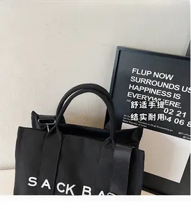 Detail of durable black canvas tote handles and adjustable nylon shoulder strap