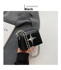 Detail of black mini crossbody bag featuring a silver metal star and ball chain strap