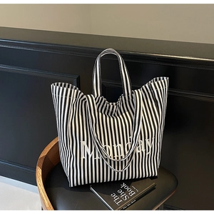 Detail of a large capacity black and white striped canvas tote bag with Monday lettering
