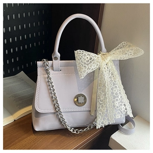 Détail du sac à main lilas en cuir verni avec nœud floral en dentelle et fermoir argenté