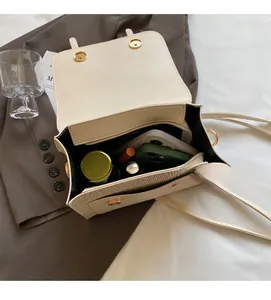 Detail view of cream white PU leather crossbody bag showing interior capacity and golden clasp