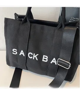 Detail view of durable black canvas sack bag with white lettering and adjustable shoulder strap