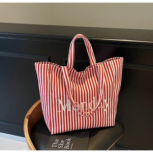 Detail of red and white striped canvas tote bag with Monday lettering on a chair