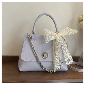 Détail du sac en cuir lilas avec un grand nœud en dentelle et un fermoir rotatif argenté