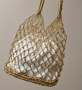 Détail du sac cabas en maille tressée dorée avec doublure à cordon blanche pour plage