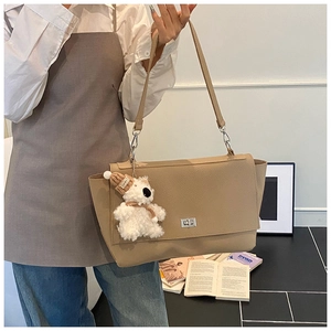 Detail of beige pebbled leather tote with silver twist lock and plush bear charm