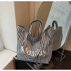 Detail shot of black and white striped canvas tote bag with Monday text on a wooden table