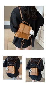 Close-up of brown textured backpack featuring woven details and a plush ball charm