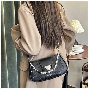 Detail of black faux-croc leather bag with heart metal buckle and silver studs