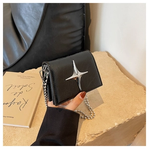 Detail of black mini crossbody bag with silver star buckle and metal bead chain strap