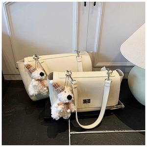 Comparison of cream leather briefcases in two sizes with plush dog charms and silver locks