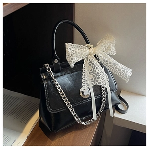 Détail d'un sac à main élégant en cuir brillant noir orné d'un grand nœud en dentelle blanche