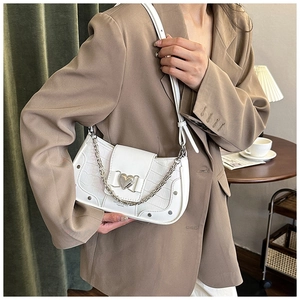 Detail of white crocodile embossed underarm bag with silver heart buckle and chain strap