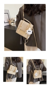 Detail view of woven texture crossbody bag with cream leather trim and plush pendant