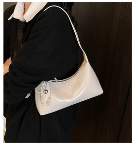 Détail du sac hobo en cuir blanc crème avec chaîne en perles et pendentif cœur en métal