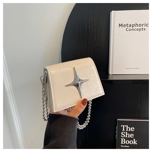 Close-up of cream mini crossbody bag with silver star ornament and beaded chain strap
